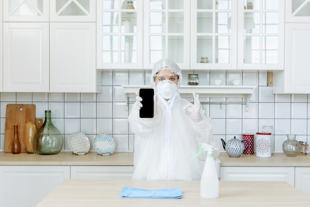 A professional pest or virus contractor stands in the kitchen\
and shows a positive sign. the concept of a pandemic coronavirus\
disinfection or covid-19