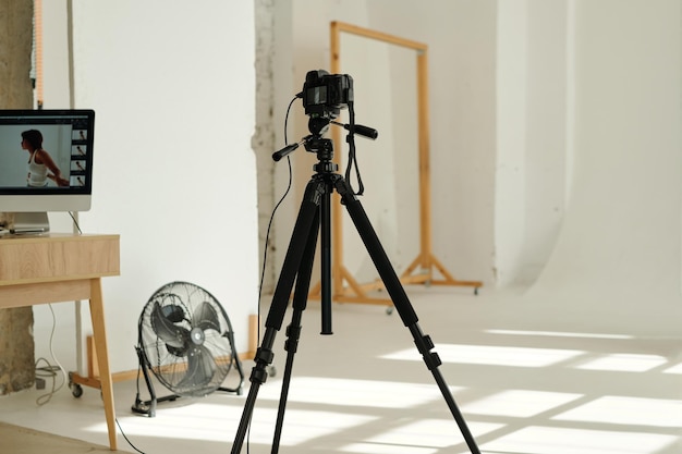 Professional photocamera on tripod standing in the center of spacious studio