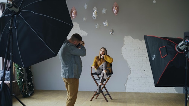 Photo professional photographer man taking photo of beautiful model girl with digital camera in studio