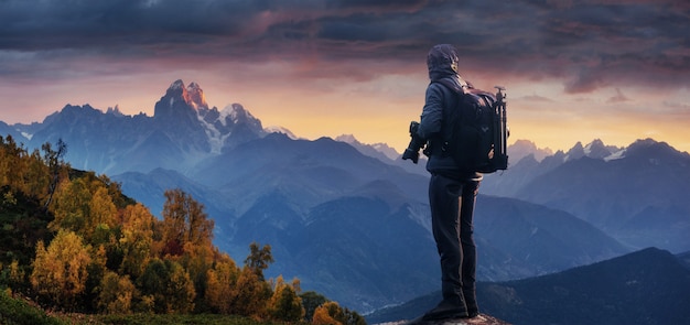 Professional photographer takes photos with big camera on peak of rock