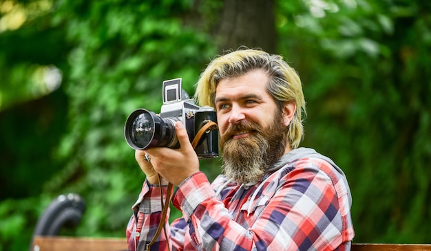 전문 사진 작가는 빈티지 카메라 수염 난 남자 힙스터를 사용하여 현대 생활 여행 팁에서 복고풍 카메라 사진으로 야외 잔인한 남자 여행자를 촬영합니다.