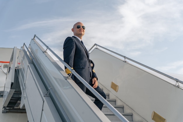 Professional pilot in sunglasses on plane ladder