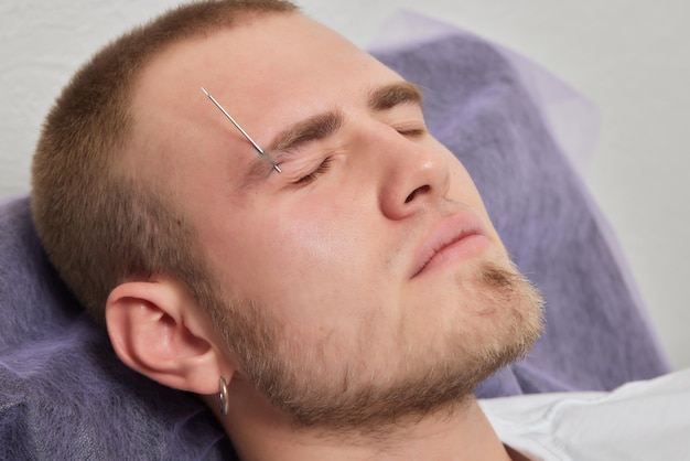 Professional placing the jewel of piercing on the temple on the head with ball Tragus type