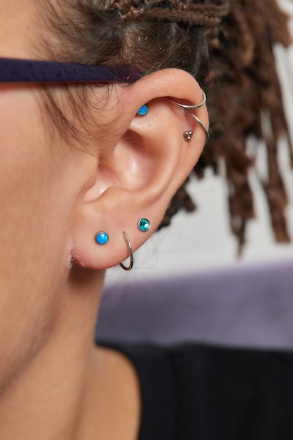 Professional placing the jewel of piercing on the temple on the head with ball tragus type