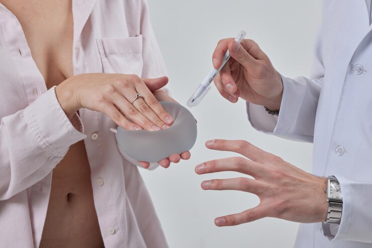 Photo professional plastic surgeon showing silicone breast implants to his female patient mastopexy concept breast lift