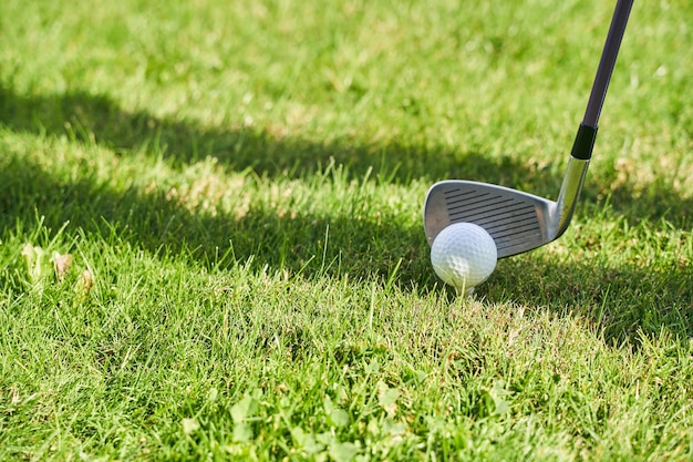Professional player hitting a white ball from the tee with a metal wedge golf club