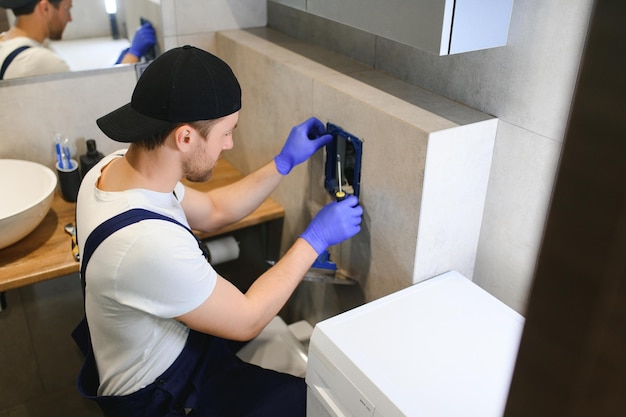 Professional plumber working with toilet bowl in bathroom