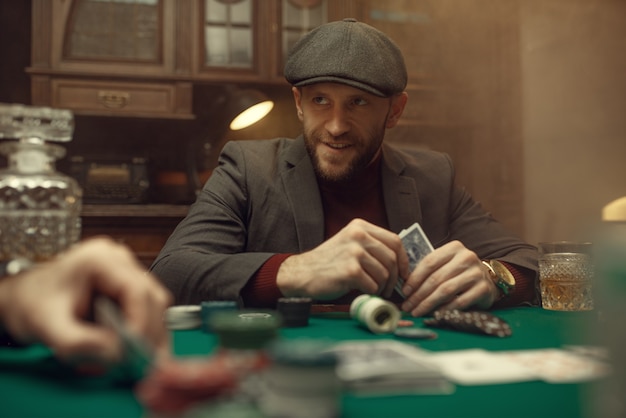 Professional poker player feels the risk. games of chance addiction. man with cards in hands leisures in gambling house