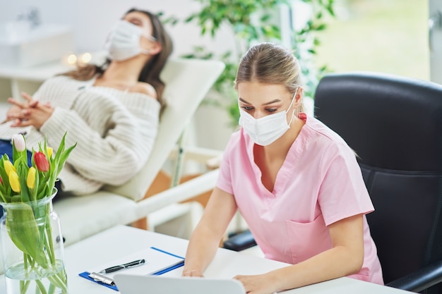 professional psychiatrist consulting her patient and making notes both in masks