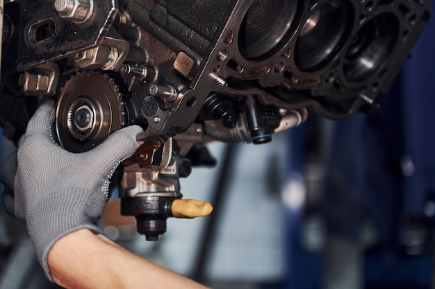 Professional repairman works with broken automobile engine