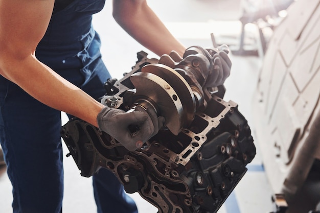 Professional repairman works with broken automobile engine