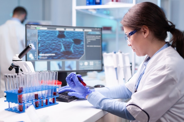 Photo professional scientist looking at analysis of blood tube for medical experiment