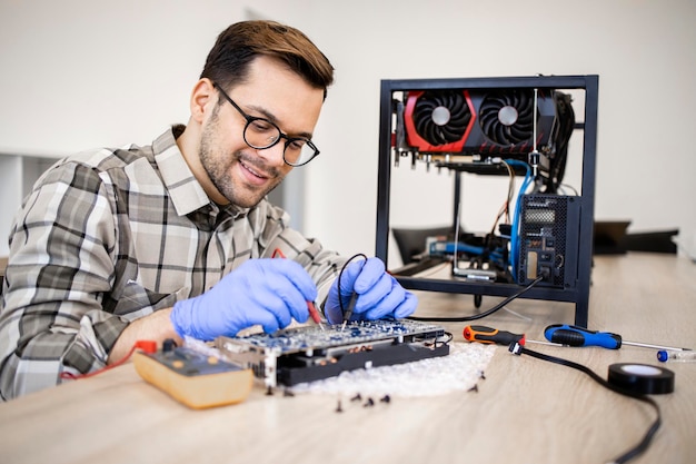 Professional serviceman repairing graphics card and checking\
voltage of printed circuit board