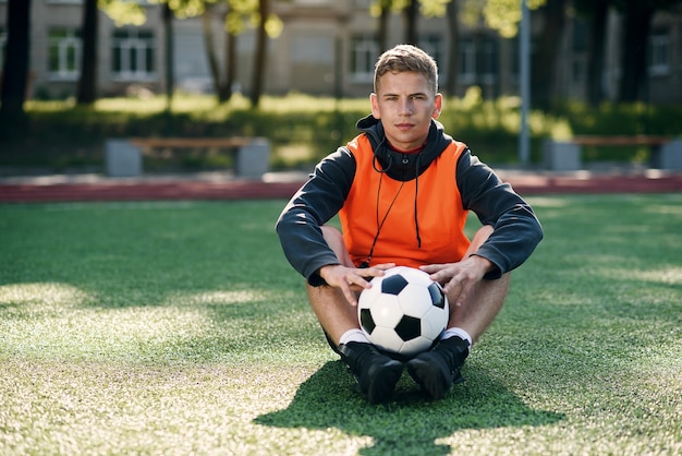 Photo professional soccer coach in an orange vest and a whistle on neck.