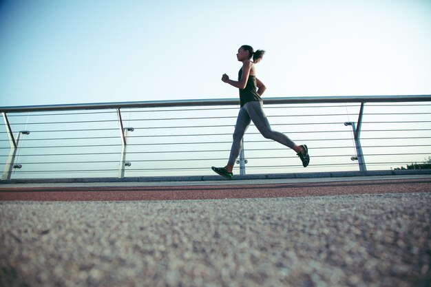 Foto sportiva professionista che corre da sola sul ponte vicino alla ringhiera