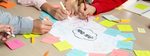 Foto gruppo di startup professionisti condividono idee di marketing creative utilizzando una mappa mentale giovani uomini d'affari qualificati fanno brainstorming sul piano di business mentre scrivono appunti adesivi concentrati sulla mano closeup variegato