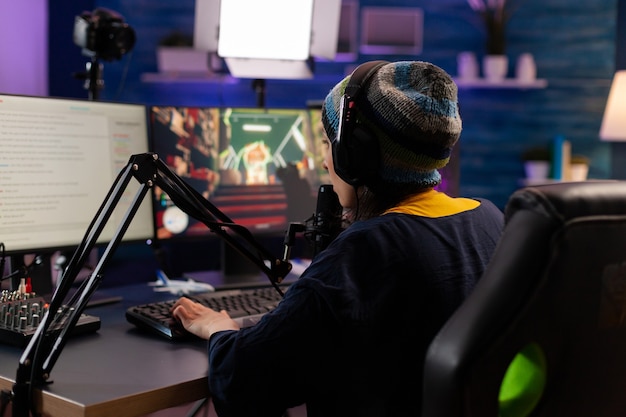 Streamer professionista che gioca a giochi sparatutto indossando le cuffie e parlando al microfono tramite chat in streaming. giocatore che crea videogiochi online con una nuova grafica su un computer potente