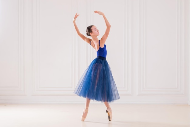 Professional student ballerina doing pointe shoes in a beautiful white room