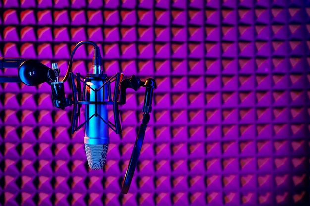 Фото Профессиональный студийный микрофон на фоне акустической пенной панели в неоновом свете