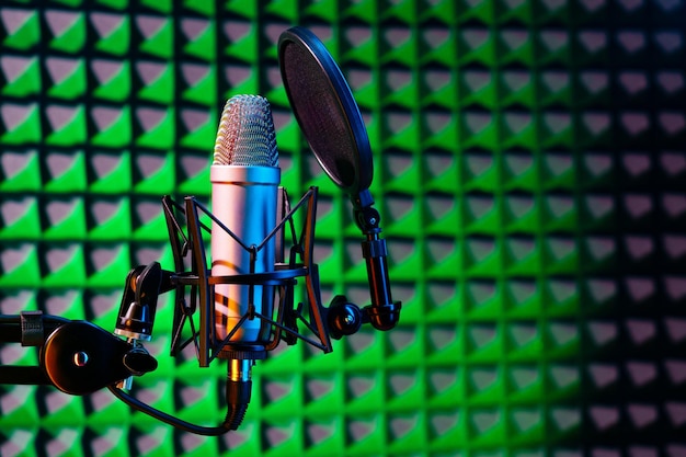Профессиональный студийный микрофон на фоне акустической пенной панели в неоновом свете