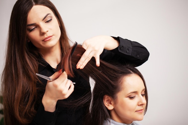 Professional stylist makes a young woman a beautiful hairstyle.