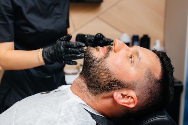 モダンでスタイリッシュな理髪店のプロのスタイリストが若い男の髪を剃り、カットします。ビューティーサロン、ヘアサロン。