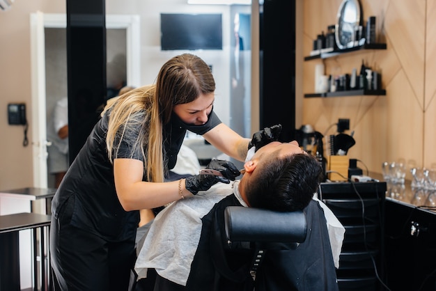 Photo a professional stylist in a modern stylish barbershop shaves and cuts a young man's hair. beauty salon, hair salon.