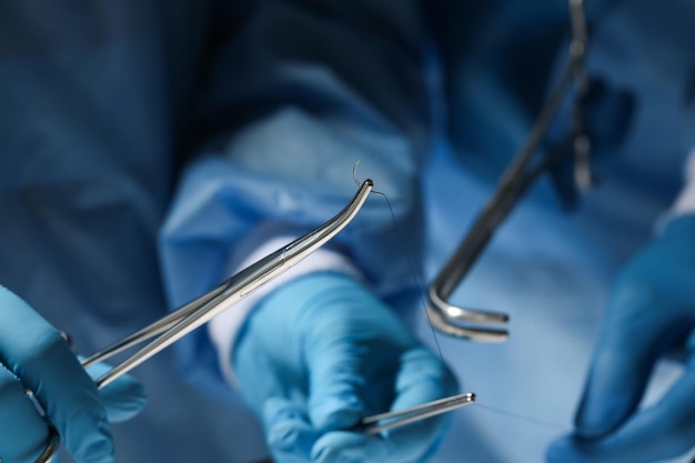 Professional surgeons with forceps and suture thread closeup Medical equipment