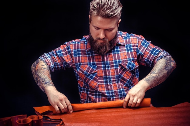 Professional Tanner cutting out leather shapes for a new product in his tanning shop