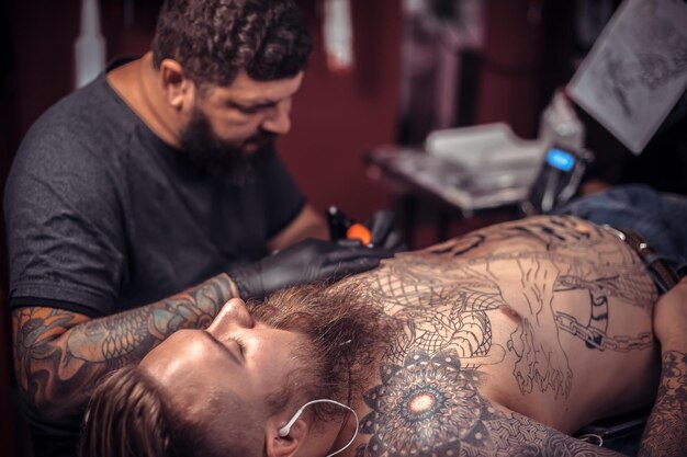 Professional tattoo artist demonstrates the process of getting tattoo his salon