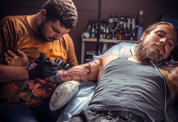 Tatuatore professionista che fa tatuaggio nel negozio di tatuaggi