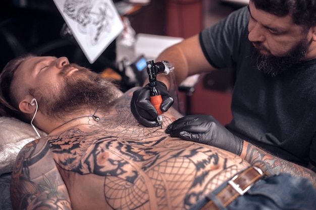 Professional tattoo artist focused on his work in his salon.