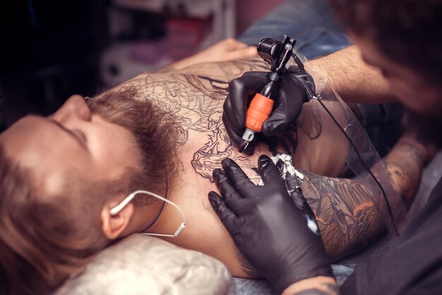 Foto il tatuatore professionista fa un tatuaggio sui clienti