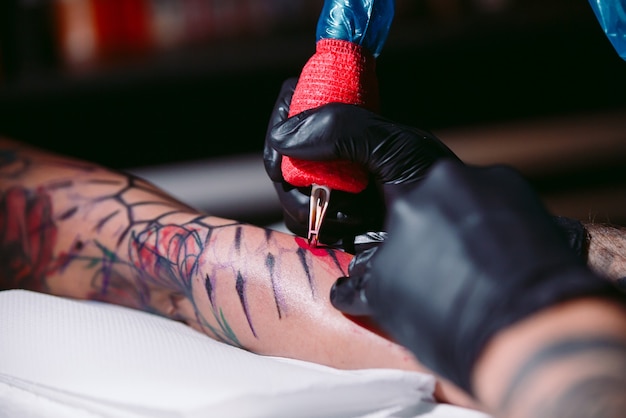 Il tatuatore professionista fa un tatuaggio sulla mano di una ragazza.