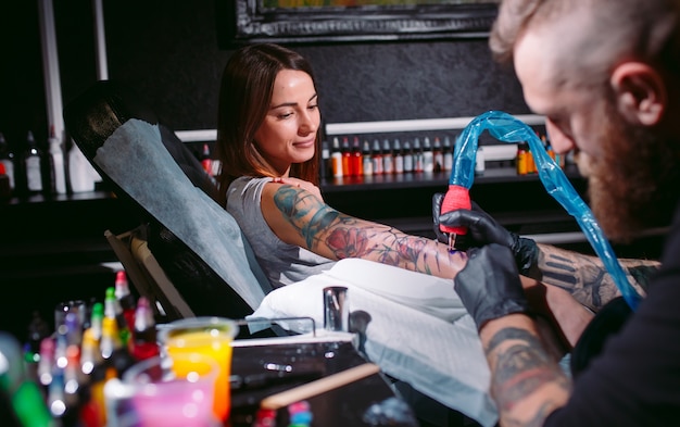 Professional tattoo artist makes a tattoo on a young girl's hand.