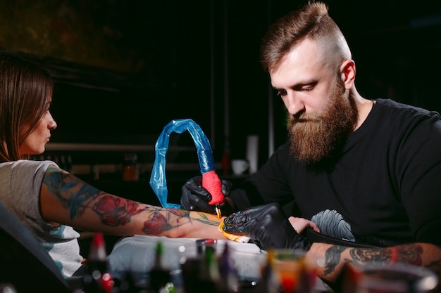 Professional tattoo artist makes a tattoo on a young girl's hand.