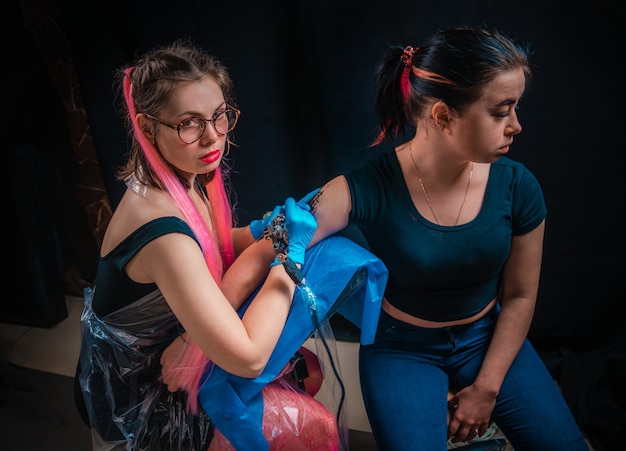 Professional tattoo artist showing process of making a tattoo