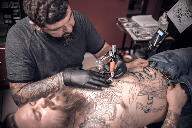 Foto il tatuatore professionista mostra il processo del tatuaggio