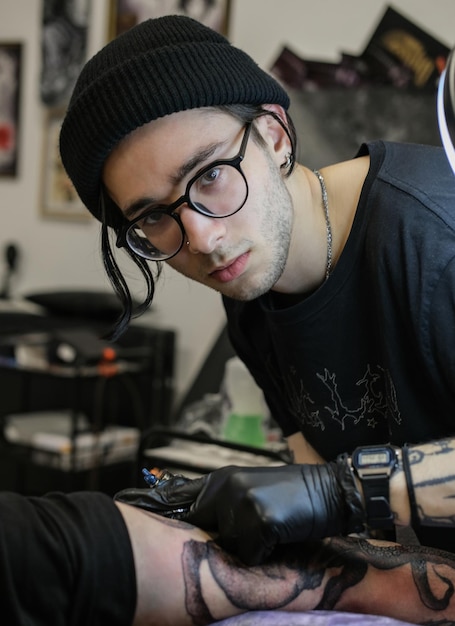 Professional tattoo artist stuffs a tattoo on the man's hand Tattoo artist at work