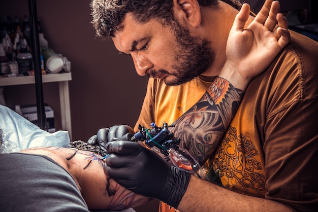 Professional tattoo artist working tattooing in studio