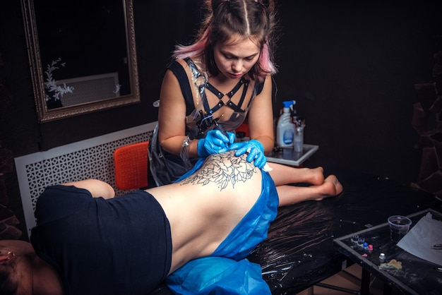 Professional tattooer makes tattoo in his salon.