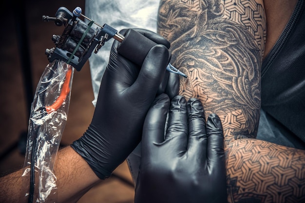 Professional tattooer makes tattoo pictures in tattoo studio./Professional tattooist makes tattoo in tatoo salon.