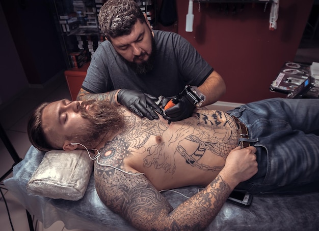 Professional tattooer making a tattoo in tattoo parlour./Tattooer doing tattoo in tattoo parlor.