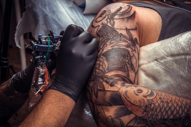 Professional tattooer works in tattoo parlor