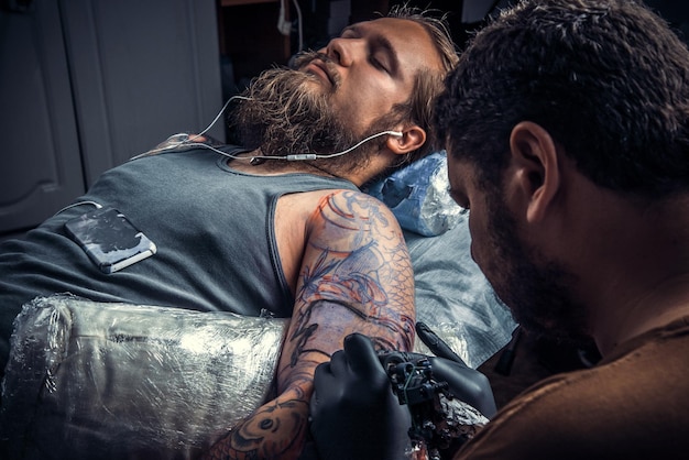 Foto tatuatore professionista crea un tatuaggio in studio di tatuaggitatuatore professionista al lavoro nel salone di tatuaggi