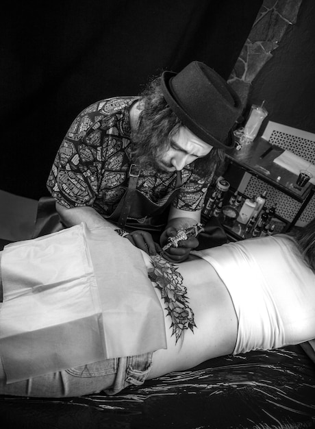 Professional tattooist doing tattoo picture in his salon