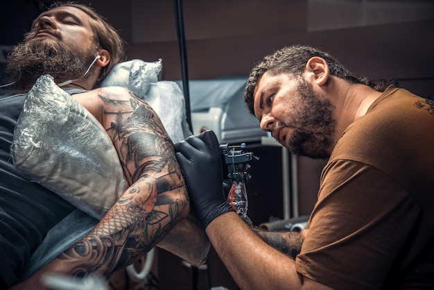 Professional tattooist posing in salon./Professional tattooer making a tattoo in tattoo parlor.