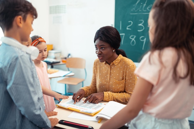 Professional teacher of primary school speaking with pupils