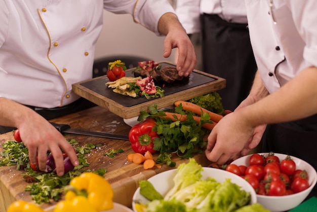 Professional team cooks and chefs preparing meal at busy hotel or restaurant  kitchen