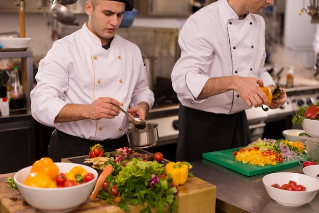 Professional team cooks and chefs preparing meal at busy hotel or restaurant  kitchen